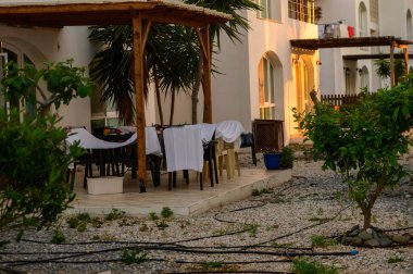 Güneş sakin bir gölün üzerinde batarken altın renkler gökyüzünü aydınlatıyor ve suya yansıyor. Siluetli ağaçlar ve uzak dağlar huzurlu bir atmosfer yaratır..