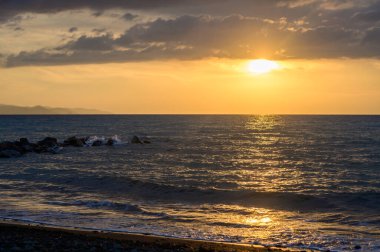 Kıbrıs kıyılarındaki sakin Akdeniz 'in üzerinde güzel bir gün batımı. Altın ışık, deniz dalgaları ve huzurlu bir atmosfer. Doğa, seyahat, deniz manzarası, akşam