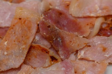 Beyaz tabakta altın çıtır çıtır kenarlı taze kızarmış pastırma şeritleri. Kahvaltı menüleri, yemek blogları veya yemek paketleme tasarımı için ideal.