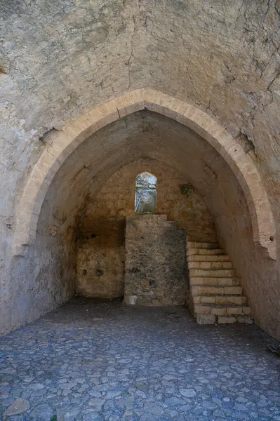 Saint Hilarion Kalesi 'nde dar bir pencereden içeri giren yumuşak ışık ortaçağ taş duvarlarına gölge düşürüyor..