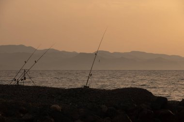 Yalnız bir balıkçı, balıkçı oltalarını Kıbrıs 'taki Akdeniz' in kayalık kıyılarına kurdu..