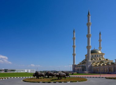 Arka planda minare ve cami olan çimlerde metal boğa heykelleri. Kuzey Kıbrıs 'ta kültürel dönüm noktası.