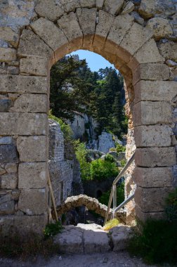 St. Hilarion Kalesi 'nin taş kemeri tarafından çerçevelenmiş göz kamaştırıcı bir manzara, çevresindeki manzarayı ve uzak dağları bir anlığına gösteriyor..