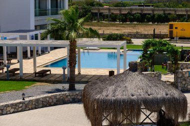 Kıbrıs 'ta güneş gözlüklü, güneşli ve palmiye ağaçlı bir sitede yüzme havuzu. Yaz atmosferi ve tatil atmosferi.