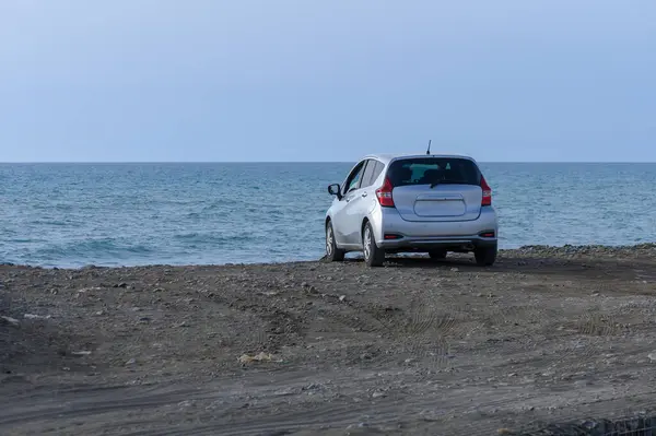 Akdeniz 'in arka planında gümüş renkli araba kıyıya yakın duruyor. Manzaralı seyahat anı.
