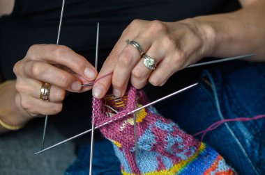 Renkli desenli çorapları elle ören bir kadının yakın çekimi. Gündüz sanatsal el yapımı..