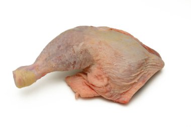 Saf bir mutfak tezgahında, çiğ bir tavuk budu çeyreği dinleniyor, doğal biçimini ve dokusunu sergiliyor. Parlak ışık tazeliği vurguluyor, mutfak yaratıcılığını davet ediyor..