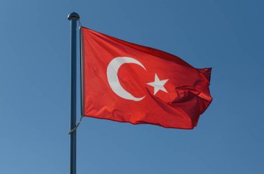Canlı kırmızı Türk bayrağı, ulusun ruhunu somutlaştıran açık mavi gökyüzüne karşı zarif bir şekilde dalgalanıyor. Hilal ay ve yıldız parlayarak Türkiye 'nin zengin kültürünü kutluyor.