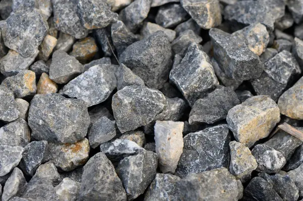 Engebeli gri taşlar bir yüzeye saçılmış, güneş ışığını yansıtıyor ve çeşitli dokular sergiliyor..