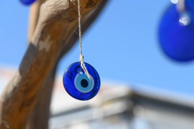 Kırsal bir daldan sarkan parlak mavi cam bir tılsım güneş ışığını canlı renklerle yansıtıyor. Açık gökyüzü büyünün büyüleyici renklerini güçlendiriyor ve büyülü bir atmosfer yaratıyor..