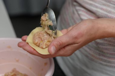 Eller dikkatlice hamur köftelerini sıcak, davetkar bir mutfakta lezzetli bir karışımla doldurur. Bu mutluluk dolu yemek pişirme seansında arkadaşlar gülümseme ve yemek tavsiyelerini paylaşırken enerji doludur..