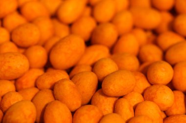 Bir sürü parlak turuncu şeker boşluğu dolduruyor. Parlak yüzeyleri, alışverişçilerin hareketli bir pazarda gezinmesi gibi hafif ışığı yansıtıyor. Tatlı koku havayı dolduruyor, geçen herkesi baştan çıkarıyor..