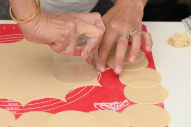 Eller ustalıkla hamur işliyor ve mükemmel daireler çiziyor. Geleneksel hamur köftelerinin temelini oluşturuyor. Sıcak mutfak, ev yapımı yemekler ve mutfak yaratıcılığına olan tutkuyu yansıtıyor..