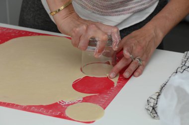 Eller bir bardağı yuvarlanmış hamura bastırır, rahat bir mutfakta mükemmel daireler çizer. Un kaplı yüzey, güneşli bir öğleden sonra keyifli bir yemek pişirme macerasına işaret ediyor..