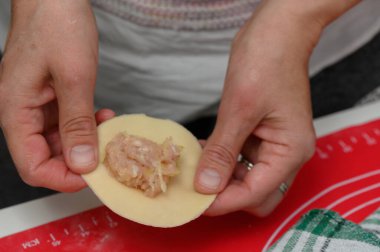 Hassas eller, baharatlı etle dolu bir hamur köftesini ustalıkla şekillendirir. Sevgi ve gelenekle dolu sıcak bir mutfakta sanatsal bir zanaat sergiler..