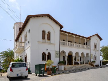 Parlak güneş ışığı, kemerli camları olan büyüleyici beyaz bir Akdeniz yapısını aydınlatıyor. Binanın çevresi yemyeşil, sakin bir sahil kasabasında güzelliğini arttırıyor..