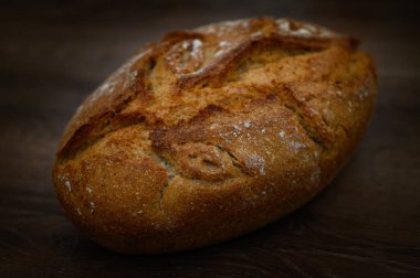 Tahıl unundan yapılmış sıcak kabuklu somun ahşap bir masaya davetkar bir şekilde oturur ve ev aroması yayar..