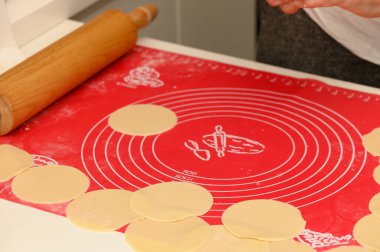 Hamur çemberleri canlı bir paspasın üzerinde düzgün bir şekilde dizilmiştir. Elleri lezzetli pişirmeye, sade bir atmosfer yaymaya hazırdır..