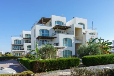 Modern bir konut binasında geniş balkonlar ve bol yeşillikler bulunur ve sakin bir atmosfer oluşturulur..