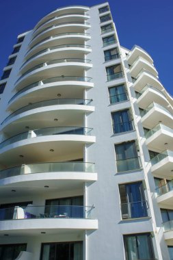 Çarpıcı bir gökdelende güneşli bir günde zarif kıvrımları ve cam balkonları olan çağdaş mimari sergileniyor..