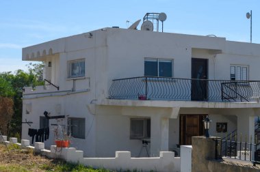 Sıcak öğleden sonra güneşiyle aydınlanan güzel beyaz bir ev belirgin bir şekilde duruyor..