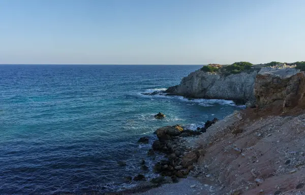 Sıcak güneş ışığı kayalıkları altın renklerde yıkarken dalgalar engebeli kıyı şeridine nazikçe yaklaşır ve sükunet yaratır..