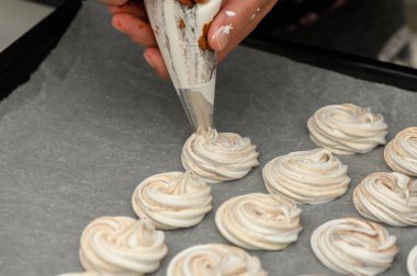 Bir el ustalıkla borular güzel krema kıvrılır parşömen kağıdına, enfes kurabiyeler yaratır pişirmek için.