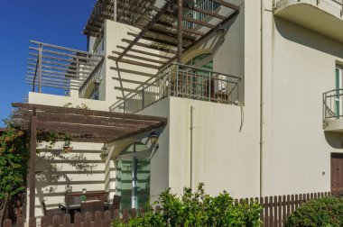 Mimari tasarım, verimli yeşilliklerle çevrili geniş bir terası olan parlak bir ev sergiliyor..