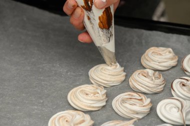 Eller ustalıkla borularla kıvrılır. Sıcak ve davetkar bir mutfak ortamında parşömen kağıdına kıvrılır..