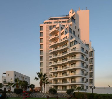 Kalın çizgiler ve gösterişli tasarım, alacakaranlıkta canlı bir gökyüzüne karşı çarpıcı bir konut binasının altını çiziyor..