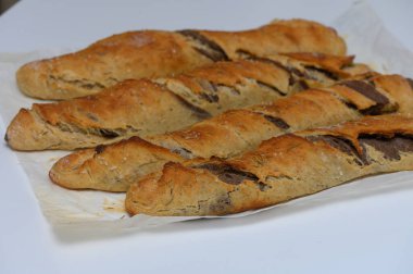 Altın-kahverengimsi ekmek somunları parşömen kağıdının üzerinde güzelce düzenlenir, kabuklu bir dış görünüş sergilerler derin kesikler ve havayı dolduran davetkar bir koku.