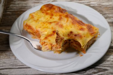 Sıcak ve davetkar lazanya, makarna katmanları, lezzetli et ve kremalı sos içerir. Mükemmel bir şekilde pişmiş, sakin bir akşam boyunca büyüleyici bir yemek masasında hevesli bir yemek bekliyor..