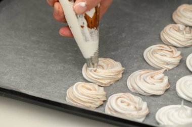 Yetenekli bir fırıncı, sıcak mutfak atmosferinde yaratıcılık ve hassasiyet gösteren tatlı krema yuvalarını süsler..