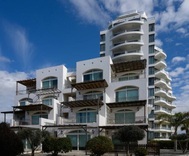 Çarpıcı bir bina, parlak mavi gökyüzüne karşı dimdik ayakta duruyor, balkonları ve çağdaş tasarım elementlerini barındırıyor..