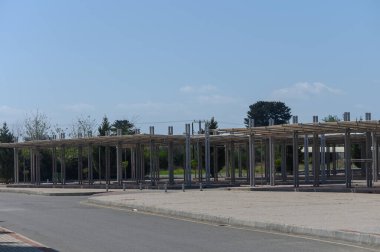 Çelik iskeletler parlak mavi gökyüzüne karşı yükselir, satıcılar ve müşteriler boşalır, gün içinde bu açık pazar alanında bir potansiyel ortamı yaratır..