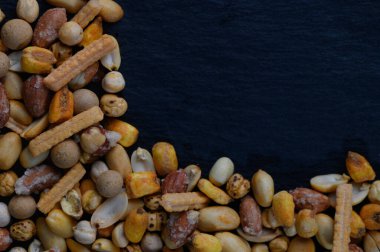 Çeşitli atıştırmalık koleksiyonları karanlık bir yüzeyin bir köşesini doldurarak çarpıcı bir kontrast oluşturur..