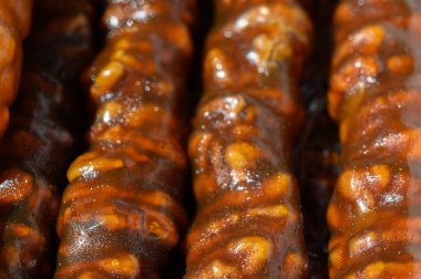 Lezzetli şekerleme, sıcak güneş ışığı altında parıldıyor ve tatlı şurupla kaplanmış karamelize edilmiş fındık karışımı sergiliyor. Yerel bir satıcı, yoldan geçenleri bu eşsiz atıştırmalığa davet ediyor..