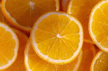 Canlı portakal dilimleri, sulu dokularını ve güneş ışığında ferahlatıcı aromalarını vurgulayan neşeli bir görüntü yaratır..