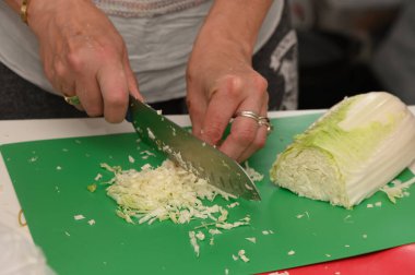 Yeşil bir kesim tahtasında lahana dilimleme ustalığı, aşçılık yeteneği ve taze malzemeler..