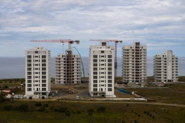 Vinçler bulutlu bir zemin üzerinde çalışırken, kıyı şeridinde yeni binalar şekilleniyor..