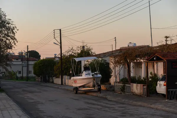Sakin bir cadde alacakaranlığın yumuşak parıltısıyla aydınlanır. Evlerle çevrili bir karavanda oturan bir tekne gibi..