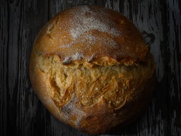 Taze pişmiş yuvarlak ekmek vitrinleri kabuklu bir üst ve rahat bir mutfak ortamında davetkar bir doku..