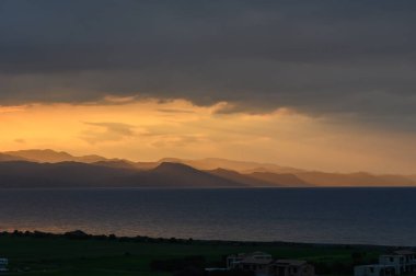 Güneş uzak tepelerin ardında batarken, denizin sakin sularını yansıtan altın renkler gökyüzüne yayıldı. Huzurlu atmosfer huzuru ve tefekküre davet eder..