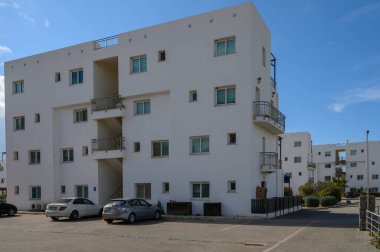 Parlak beyaz mimari tasarımlar berrak mavi gökyüzü altında sükuneti davet eden sakin bir şehir ortamı yaratıyor..