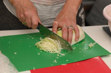 Canlı bir yemek kursunda rengarenk bir kesim tahtasının üzerinde ustalıkla taze lahana dilimler..