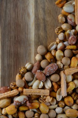 Fındık, tohum ve çıtır çıtır atıştırmalıkların canlı bir karışımı ahşap bir tahtada yaratıcı bir şekilde sergileniyor ve sıcaklık ve rahatlık hissi uyandırıyor. Toplantılar sırasında paylaşmak için mükemmel.