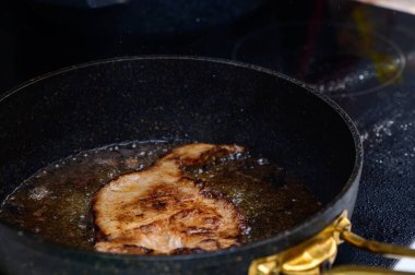 Lezzetli bir domuz pirzolası sıcak yağda cızırdar, yemek hazırlıkları sırasında mutfağı ağız sulandıran aromalarla doldurur..