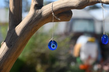 Güneş ışığı yaprakların arasından süzülürken mavi cam tılsımlar ağaçtan sarkan bir dalda sallanıyor. Büyüleyici renkleri yeryüzünün tonlarına karşı, sakin ve büyüleyici bir atmosfer yaratıyor..