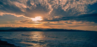 Altın ve kehribar rengi ışık okyanusun üzerine dökülür, alacakaranlıkta kıyıya nazikçe vuran dalgaları aydınlatır..