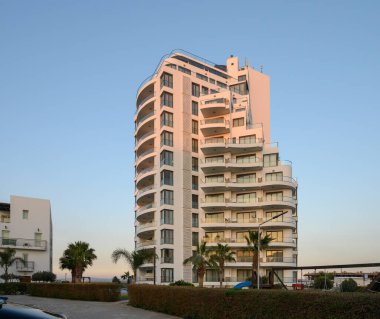 Zarif bina berrak bir gökyüzüne karşı dimdik duruyor, günbatımının sıcak parıltısını yansıtıyor, rahatlamaya ve lükse davet ediyor..